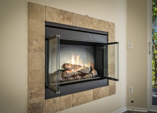 a fireplace with a glass door and rocks in the fireplace at The Village Apartments, Van Nuys California