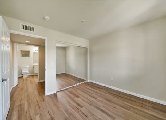 a bedroom with hardwood floors and white walls at Toscana Apartments, Van Nuys California