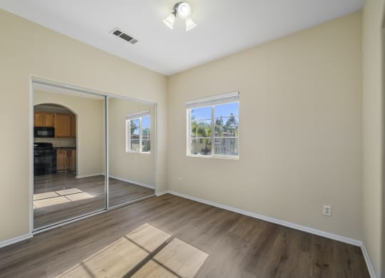 a bedroom with hardwood floors and beige walls at The Village Apartments, California, 91406