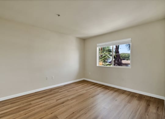 a bedroom with hardwood floors and a large window at Toscana Apartments, Van Nuys, 91325