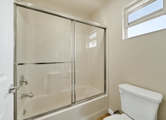a bathroom with a white toilet next to a shower with a glass door at Toscana Apartments, California, 91406
