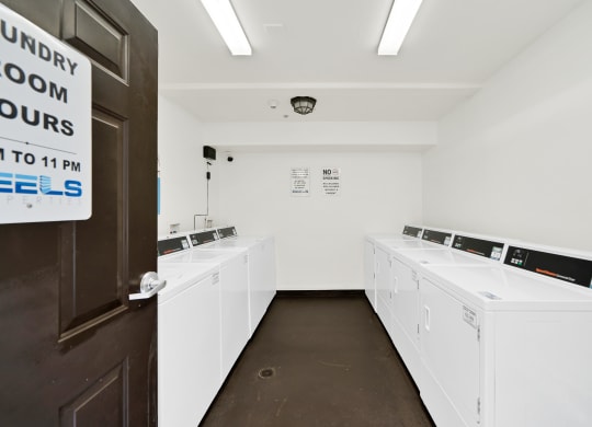 a laundry room with white washers and dryers at Toscana Apartments, California