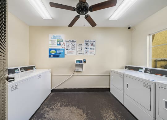 a washer and dryer room with a ceiling fan at The Village Apartments, California