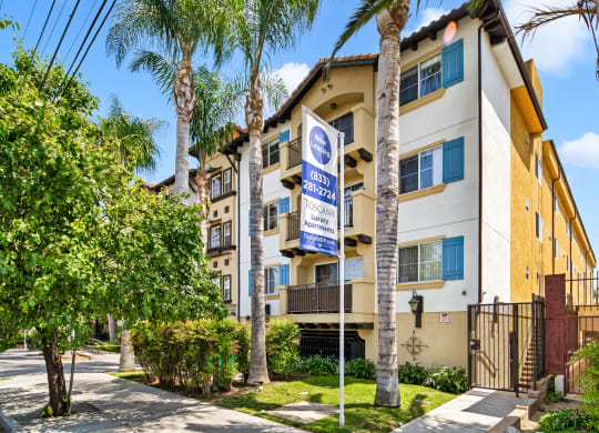 an apartment building with palm trees and a blue and white street sign