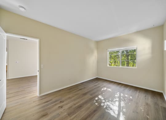 a bedroom with hardwood floors and beige walls at The Village Apartments, Van Nuys California