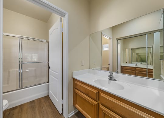 a bathroom with a large mirror and a large sink at The Village Apartments, Van Nuys, 91406