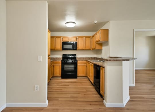 an empty kitchen with wood flooring and black appliances