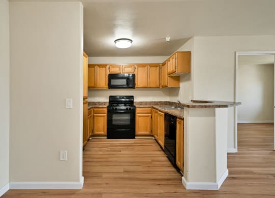 a kitchen with wooden cabinets and black appliances at Toscana Apartments, California, 91406