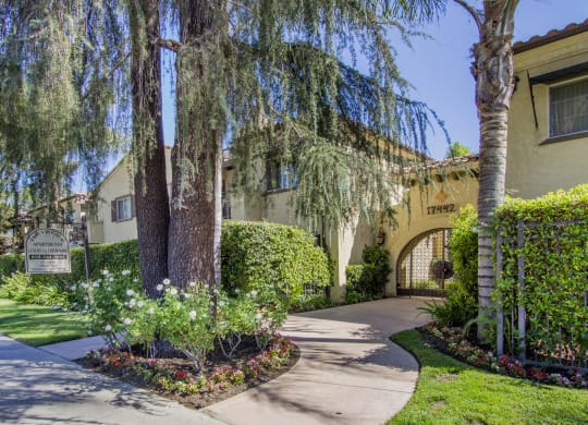 a sidewalk in front of a building with trees and flowers