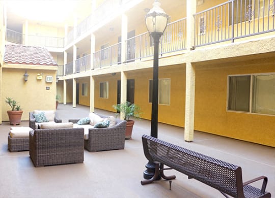 courtyard with brown furniture and yellow walls at Toscana Apartments, California, 91406