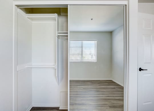 an empty bedroom with a closet and a window