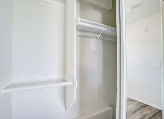 an empty closet with white walls and a white closet door