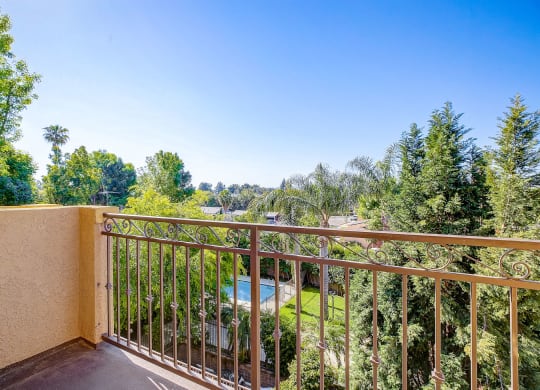 a balcony with a view of a pool and trees