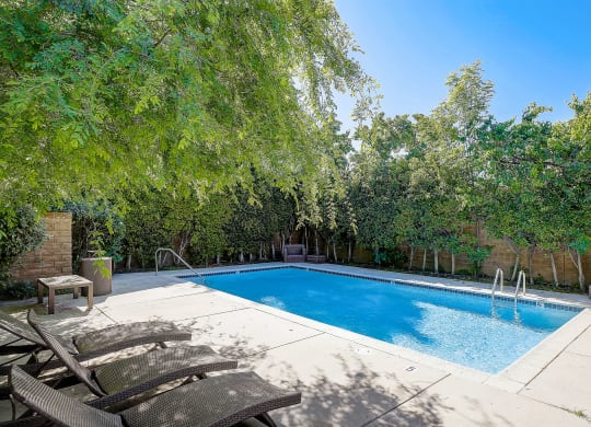 a swimming pool with two chairs next to it