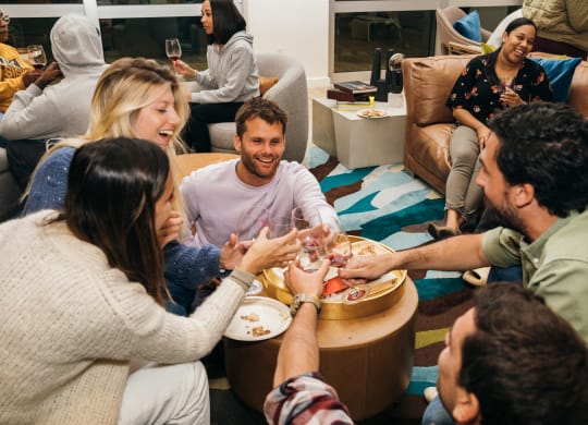 a group of people sitting around a table eating food and drinking wine