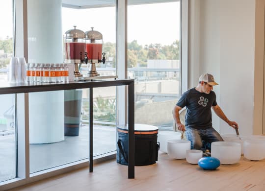 a man kneeling on the floor stirring buckets in a room