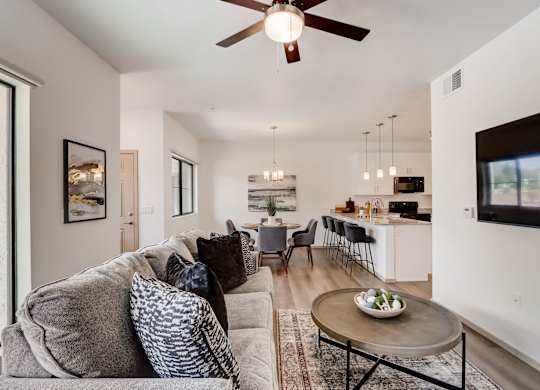 A living room with a grey couch and a ceiling fan.