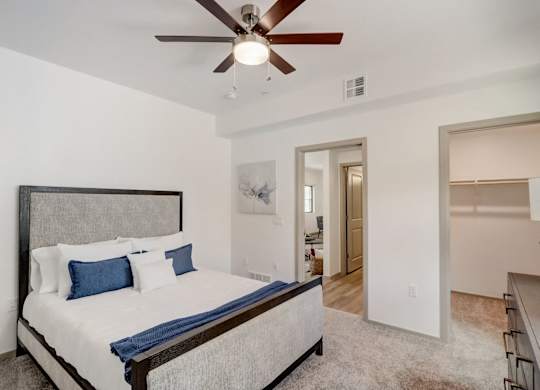 A bedroom with a bed, a ceiling fan, and a nightstand.