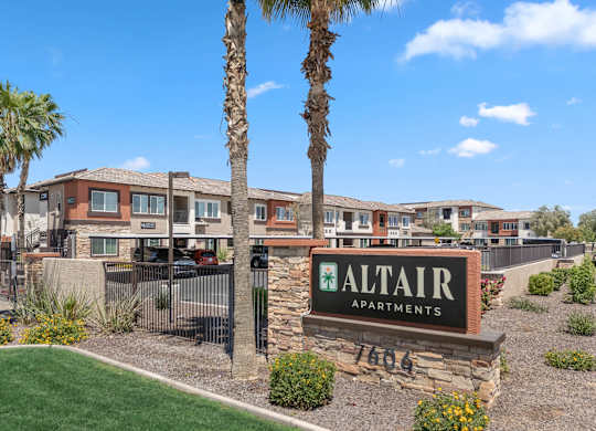 A sign for Altair Apartments is in front of a building with a palm tree.