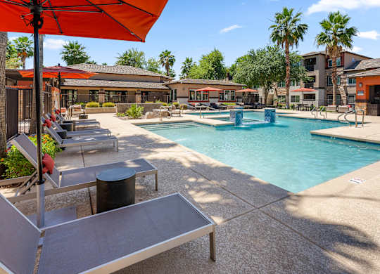 A pool area with a red umbrella and a small pool.