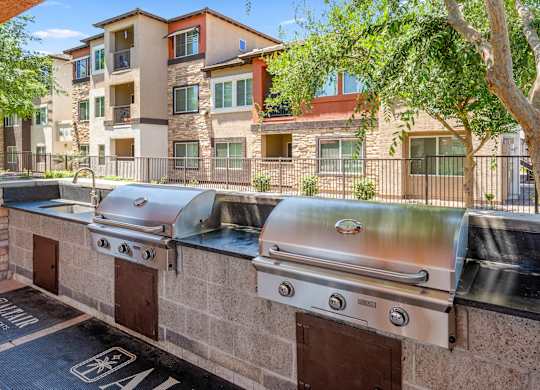 Outdoor BBQs are lined up on a brick wall.