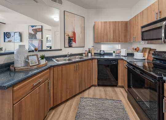 A modern kitchen with wooden cabinets and black appliances.