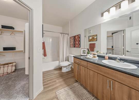 A bathroom with a toilet, sink, mirror, and a shower.
