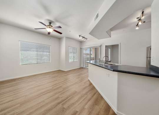 A room with a ceiling fan and wooden flooring.