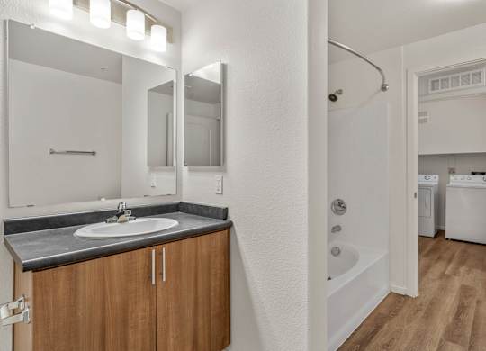 A bathroom with a sink, mirror, and a tub.