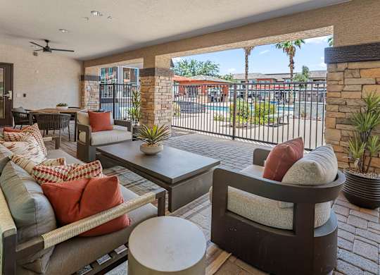 A patio with a couch, chairs, and a table with a potted plant.
