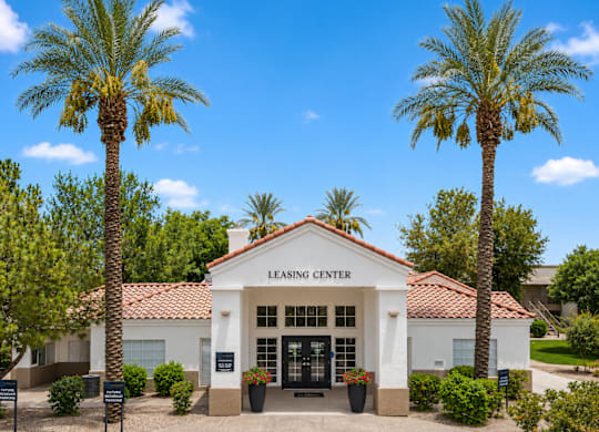 A white building with a red tile roof and a sign that says