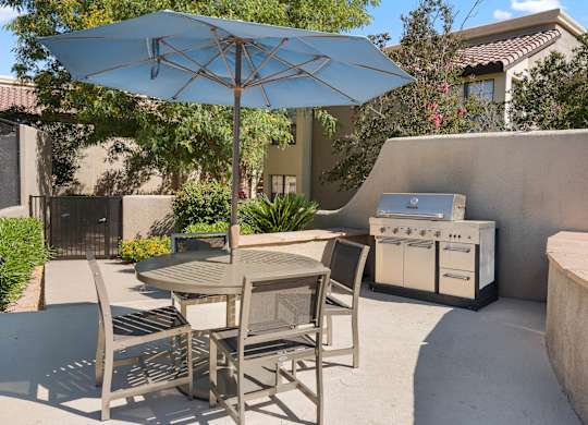 A patio with a table, chairs and an umbrella.