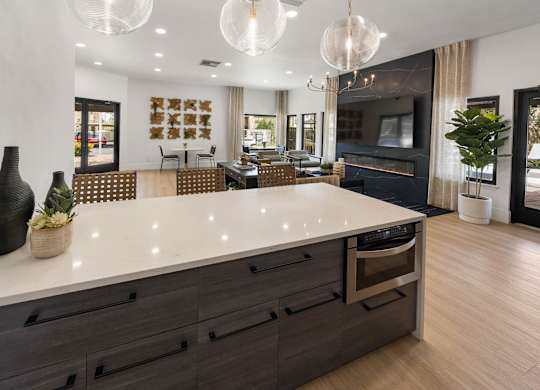A modern kitchen with a large island and a dining area in the background.