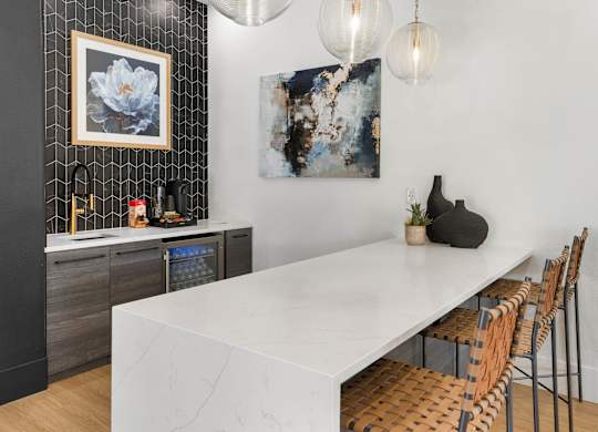 A modern kitchen with a long white table and chairs.
