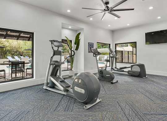 A spacious home gym with a treadmill, elliptical trainer, and stationary bike.