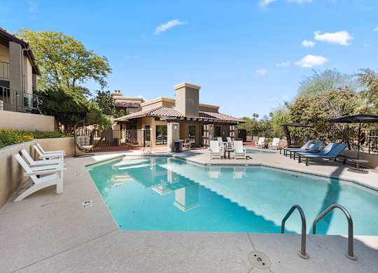 A swimming pool surrounded by lounge chairs and umbrellas.