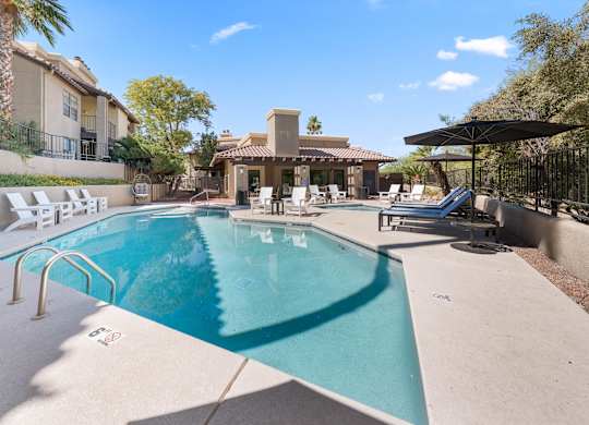 A swimming pool in a backyard with a patio and a pool house.