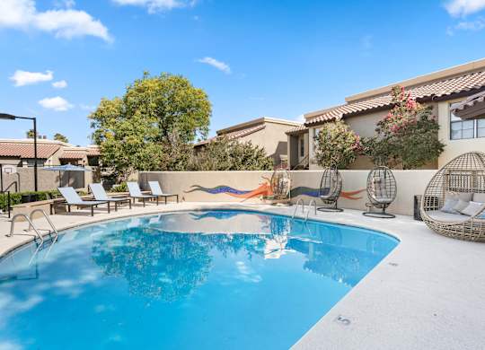 A pool with a white background and a house in the background.