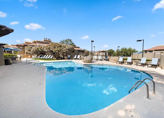 A large outdoor swimming pool with a sun lounger and poolside table.