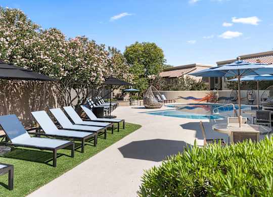 A pool area with sun loungers and umbrellas.