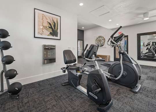 A gym room with a row of exercise bikes and a mirror.