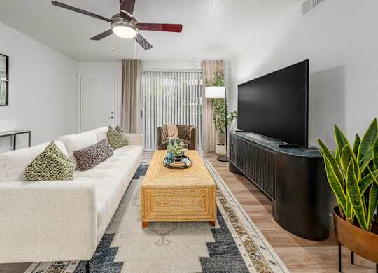 A living room with a white couch, a wooden coffee table, and a flat screen TV.