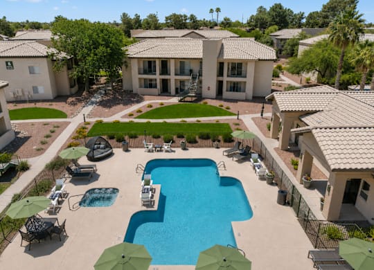 A swimming pool surrounded by a few chairs and umbrellas.