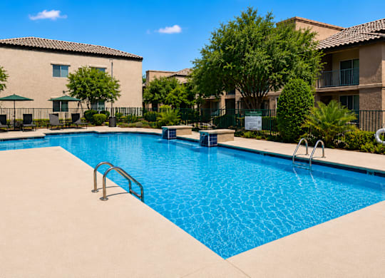 A swimming pool surrounded by a fence and trees.