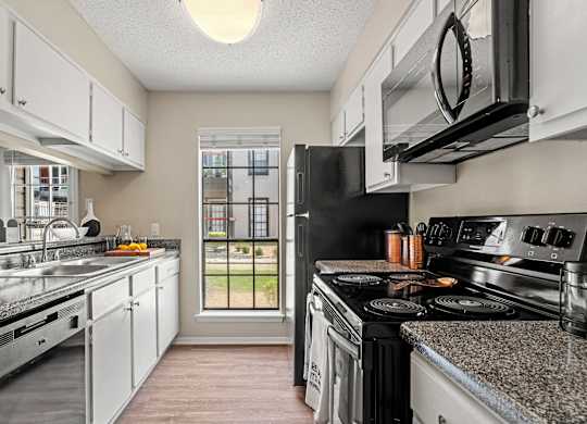 A kitchen with black appliances and white cabinets.