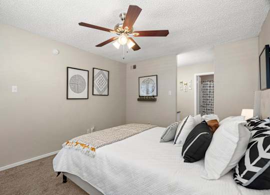 A bedroom with a bed, pillows, and a ceiling fan.