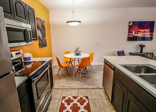A kitchen with orange walls and a table set for two.