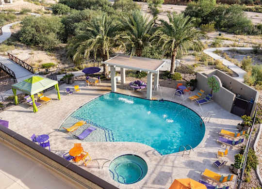 A pool with a gazebo and chairs around it.