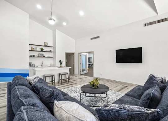 A living room with a grey sofa and a television on the wall.