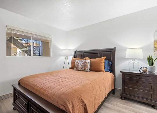 A bedroom with a bed, nightstand, and a window.